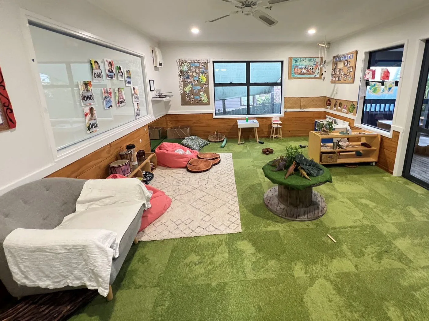 Open play space in the Fantail Room with cushions, a low bed and tree stump tables
