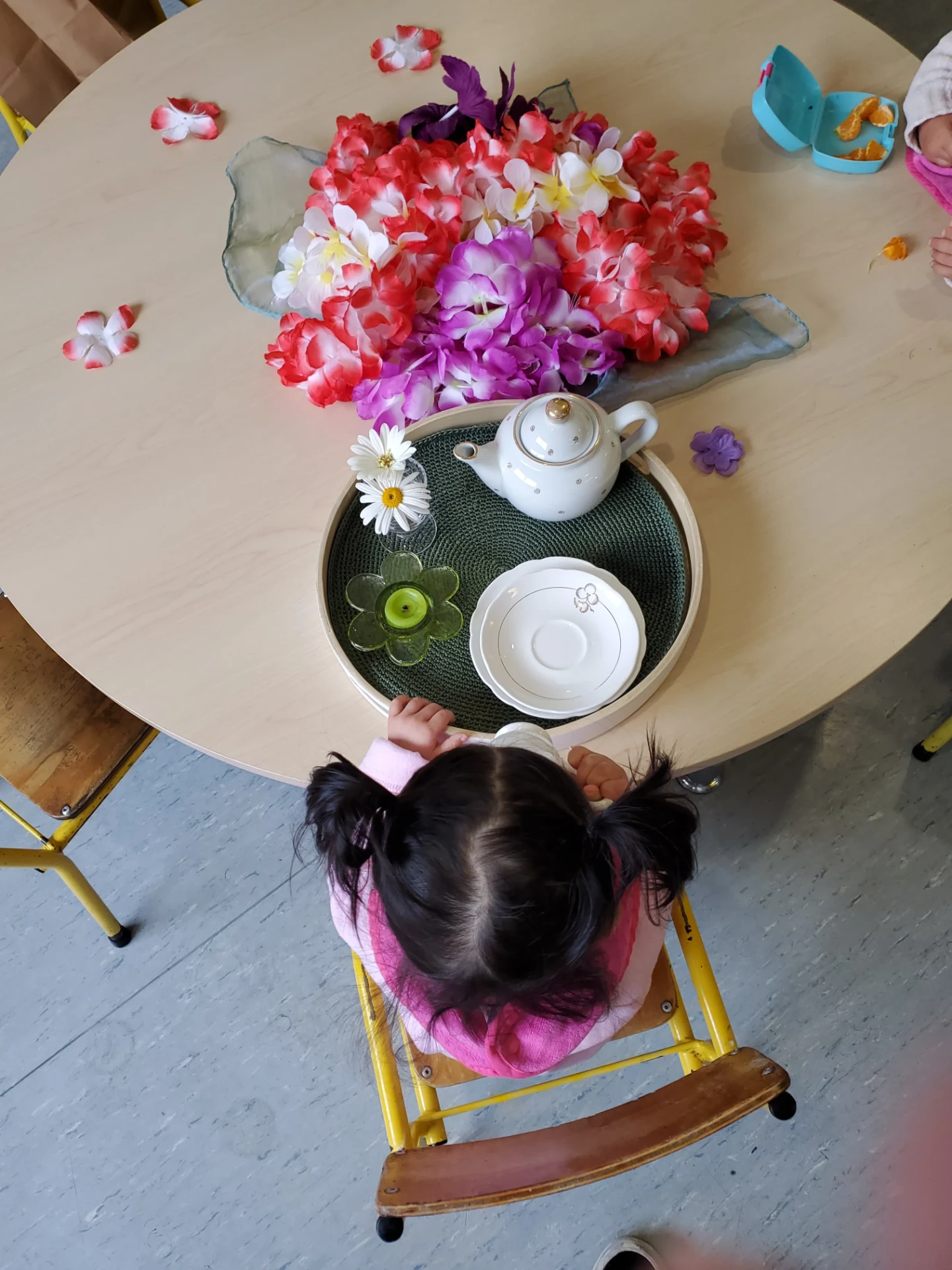 A child at Growing Minds enjoying a flower tea party ritual at a low table